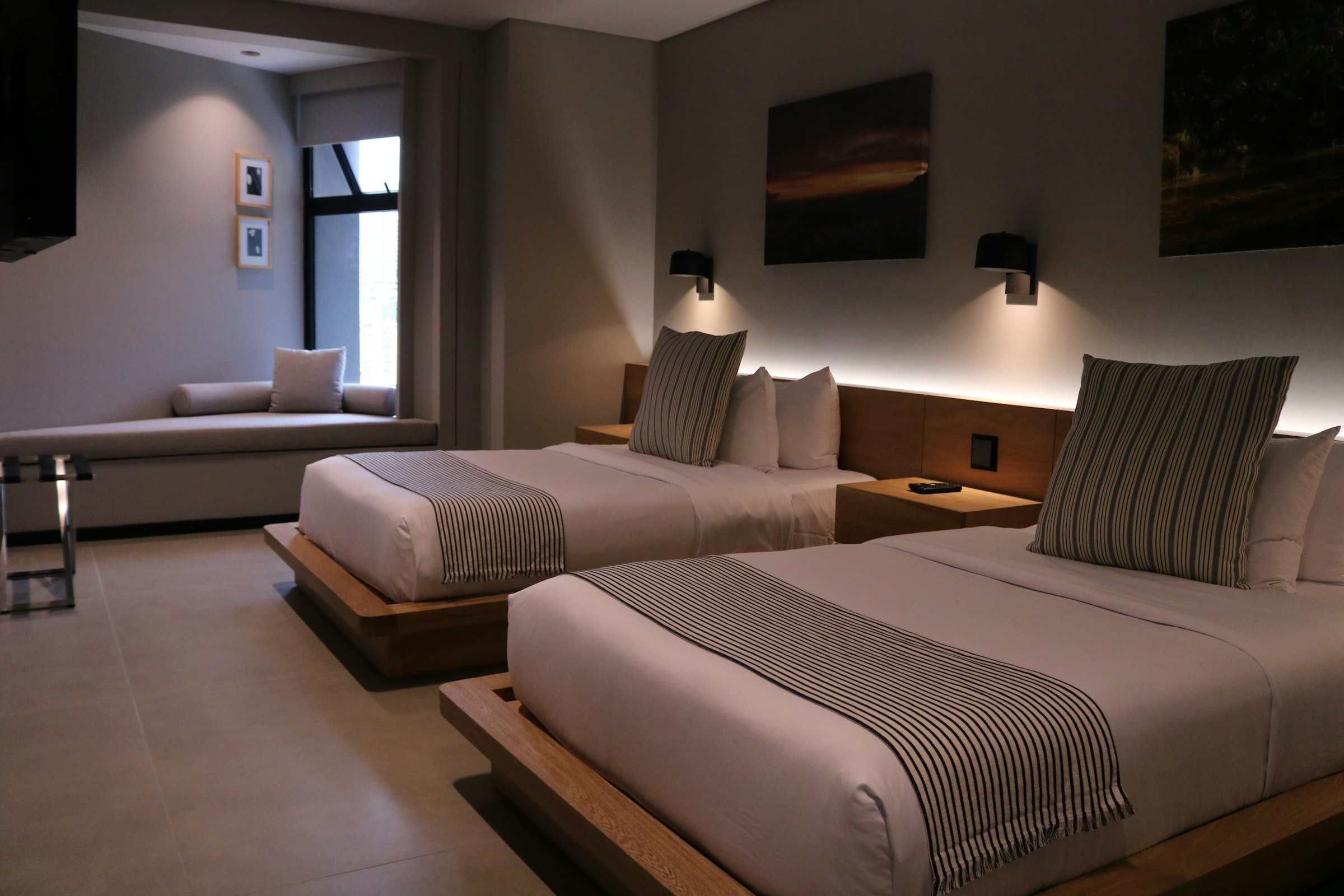 A hotel guest room with two assembled beds, a couch and case goods